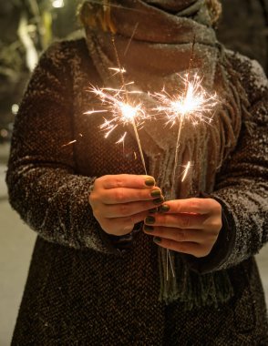 Maytap portre siyah arka plan üzerine el yanan yeni yıl partisi. Kadın ateş etmek parlayan parlayan tatil parlak el havai fişek, tutar. Noel ışık.