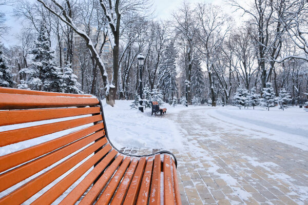 A snow covered bench in a park