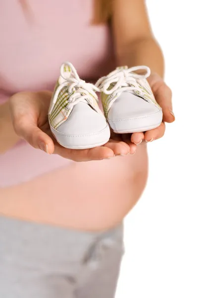 Pregnant woman holding pair of white shoes for baby (Shallow do — Stock Photo, Image
