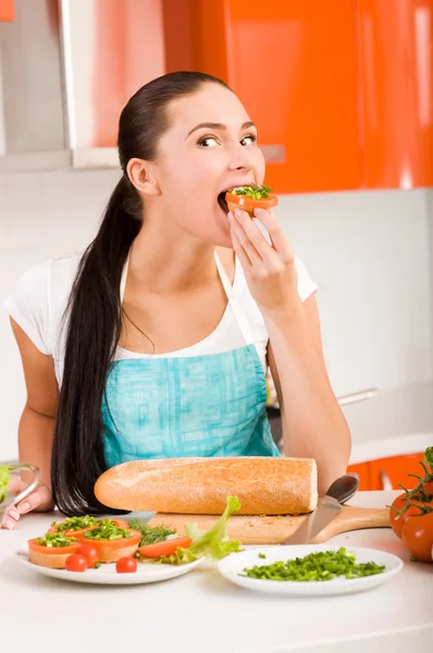 Atractiva mujer degustando sándwiches frescos y saludables en su cocina —  Fotos de Stock