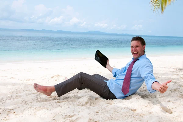Счастливый бизнесмен сидит и работает на пляже с планшетом — стоковое фото