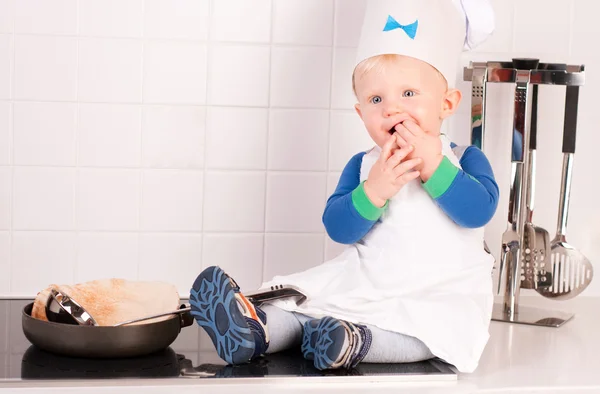Kleine baby chef-kok in de hoed van de kok maken de pannenkoeken — Stockfoto