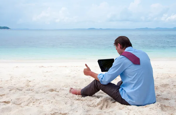 Hombre de negocios sentado y trabajando en la playa con tablet comput Imagen de archivo