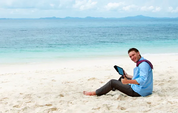 Obchodní muž sedí a pracuje na pláži s tablet počítačů — Stock fotografie