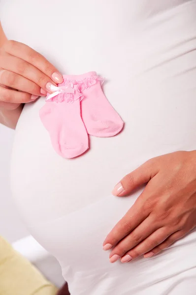Bauch einer schwangeren Frau mit Babysocken — Stockfoto