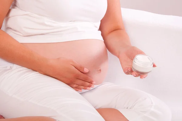 Mujer embarazada aplicando crema en su vientre — Foto de Stock