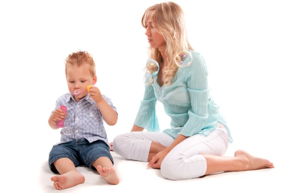 Porträt einer glücklichen Mutter mit einem fröhlichen Sohn, der mit Seifenblasen spielt — Stockfoto