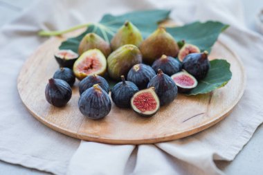 Tahta bir tabakta olgun yeşil ve mavi incirler.