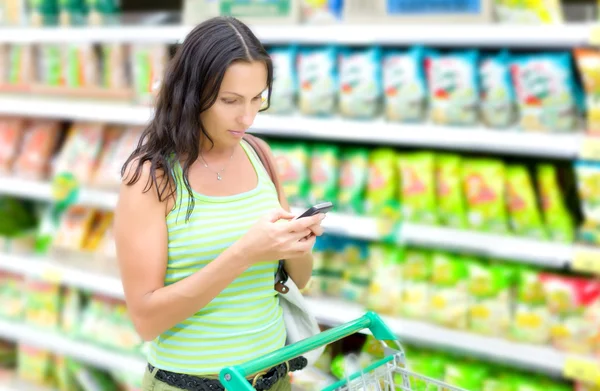 Uma mulher lê SMS em supermercados Imagens De Bancos De Imagens