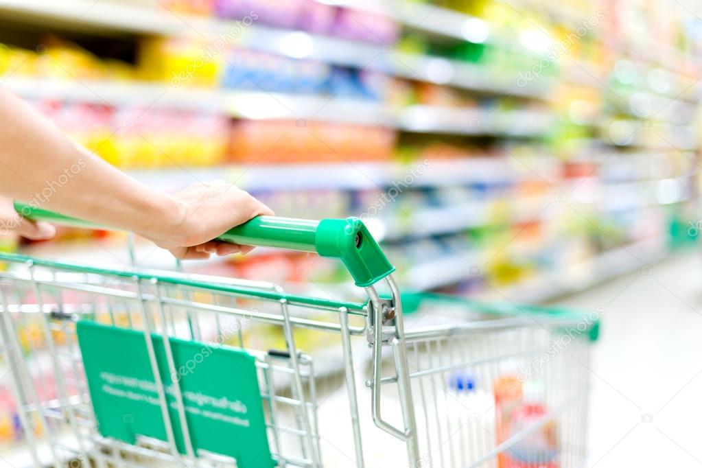 Cropped image of female shopper with cart at supermarket