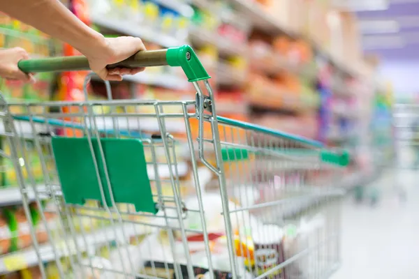 Cliente feminino faz compras no supermercado com carrinho — Fotografia de Stock