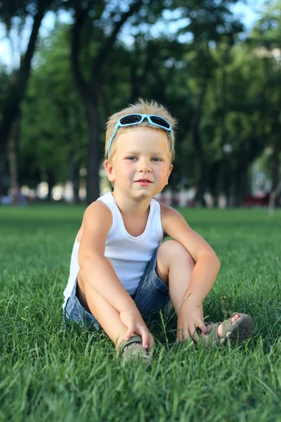 Little boy sitting in the park — Stock Photo, Image