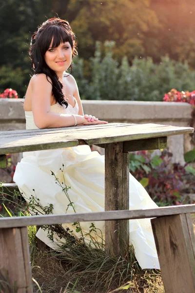 Girl in the wedding dress sitting on the bench — Stock Photo, Image