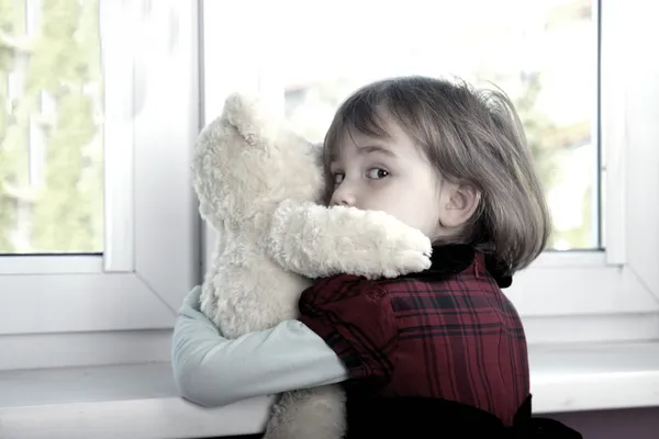 Asustada niña abrazando oso de peluche — Foto de Stock