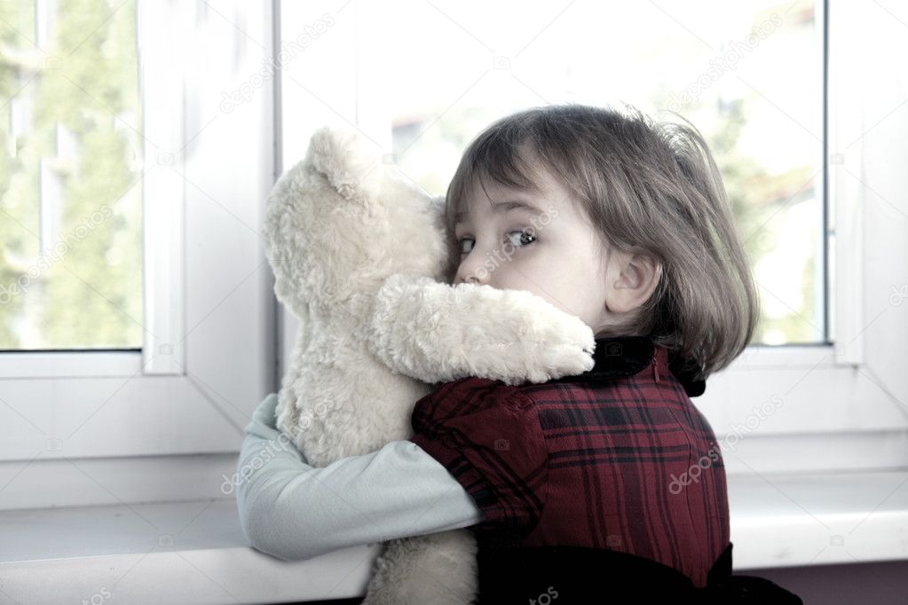 Frightened little girl hugging teddy bear