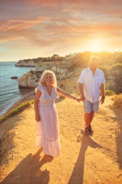 Aşık yaşlı bir çift uçurumlarda okyanus kenarında yürür. 