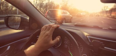 Şöför güzel bir günde şehirde arabasını sürüyor.