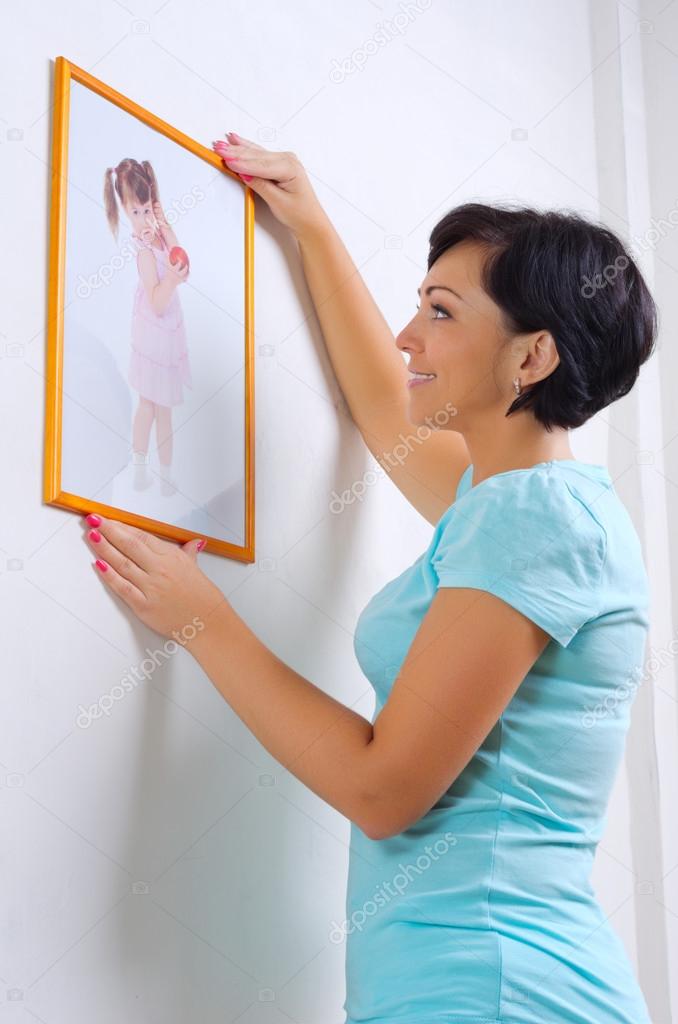 Woman hanging up photo of little girl