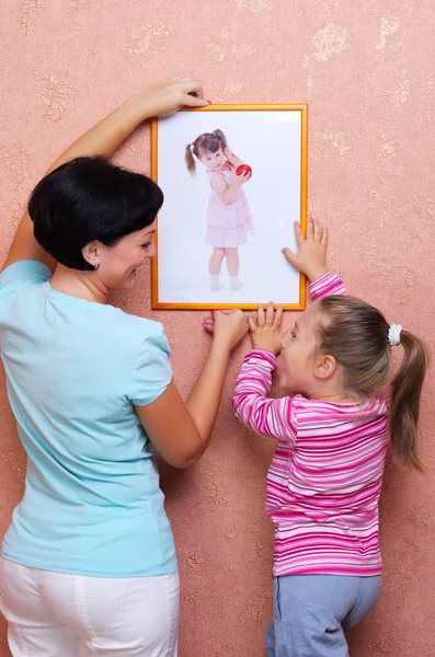 Woman and girl hanging up the picture — Stock Photo, Image