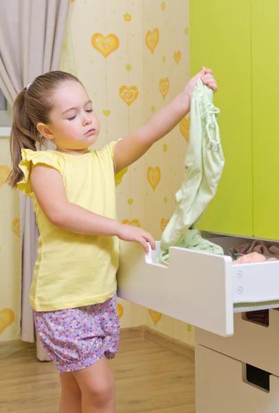 Flicka sätta en kläder för kryssrutan gemener i ett hem — Stockfoto