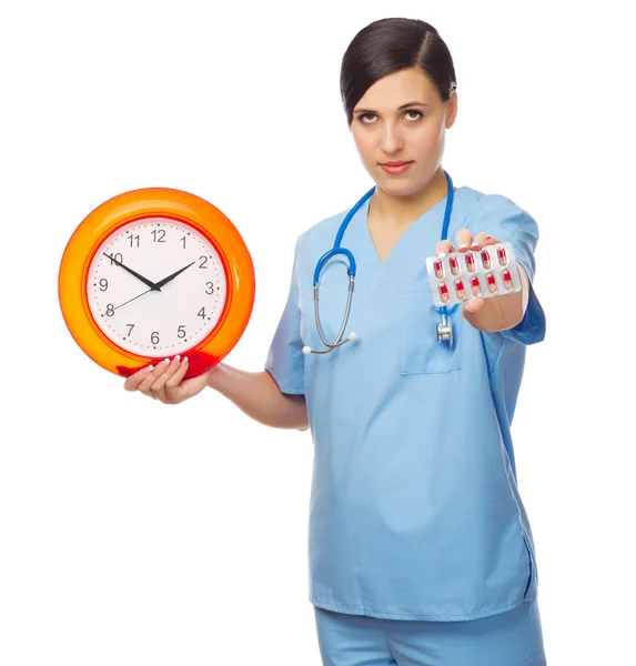 Junge Ärztin zeigt rote Pillen und Uhr — Stockfoto