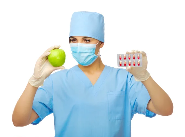Junge Ärztin mit grünem Apfel und Pillen — Stockfoto