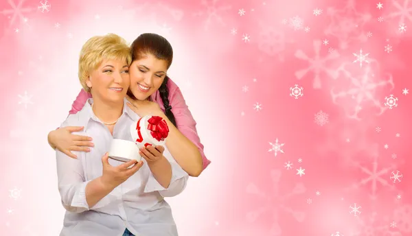 Young girl giving gift to her mother on winter background — Stock Photo, Image