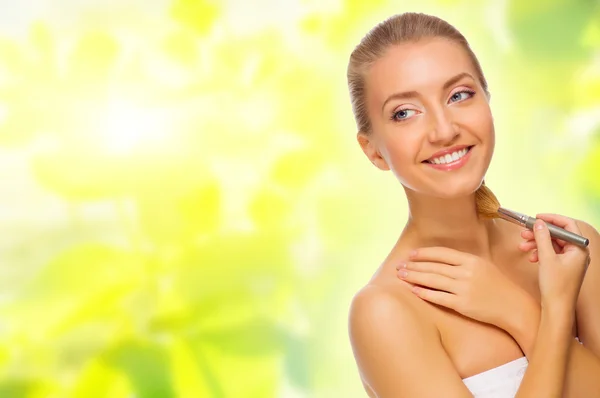 Young woman with makeup brush on spring background — Stock Photo, Image