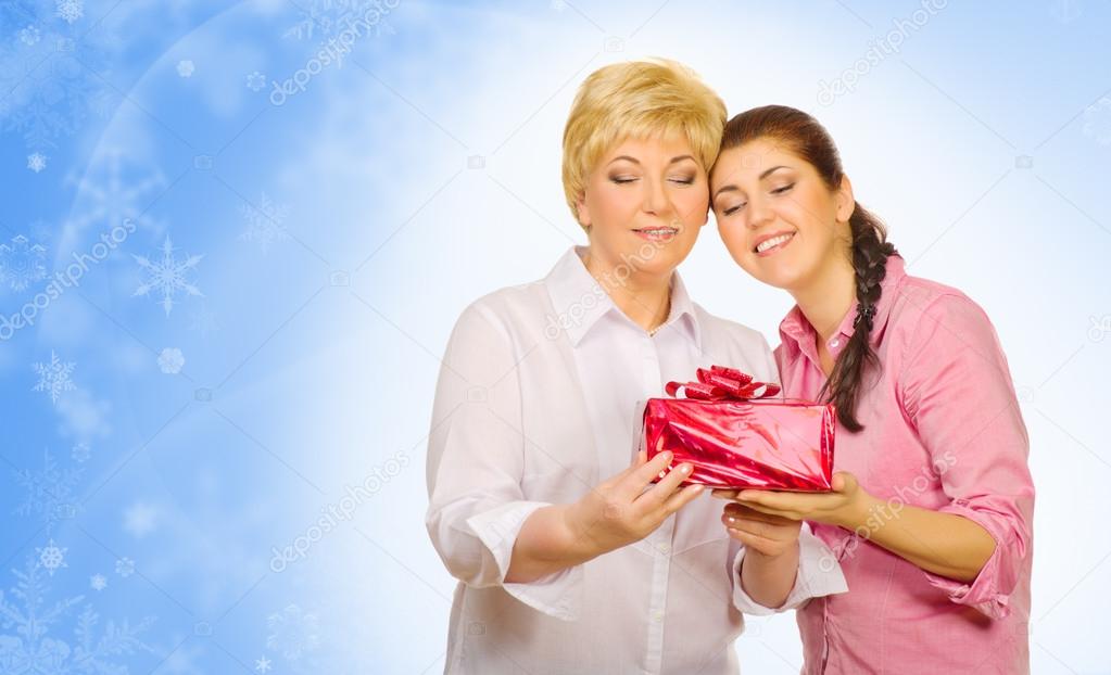 Young girl giving gift to her mother on winter background