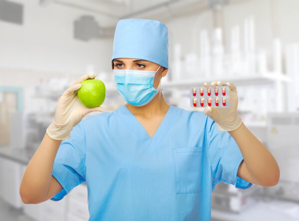 Young doctor with apple and pills