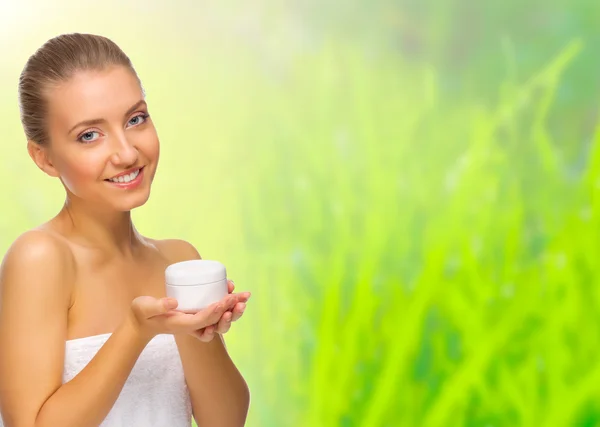 Young healthy girl with body cream jar on spring background — Stock Photo, Image