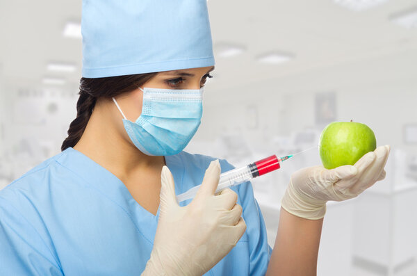 Young chemist with apple and syringe