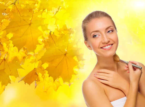 Girl with makeup brush on autumnal background — Stock Photo, Image