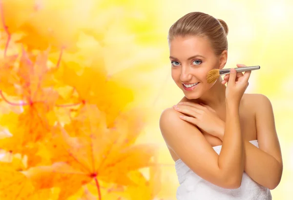 Meisje met make-up borstel op herfst achtergrond — Stockfoto