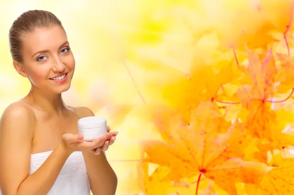 Healthy girl with cream jar on autumnal background — Stock Photo, Image