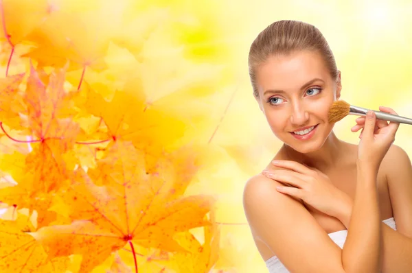 Young girl with makeup brush on autumnal background — Stock Photo, Image