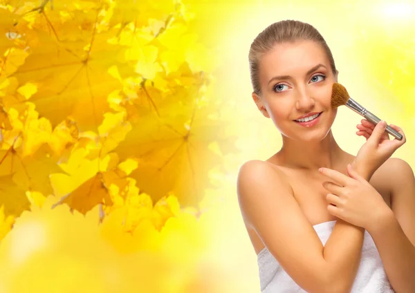 Flicka med makeup borste på hösten bakgrund — Stockfoto