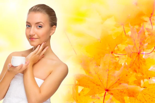 Healthy woman with body cream on autumnal background — Stock Photo, Image