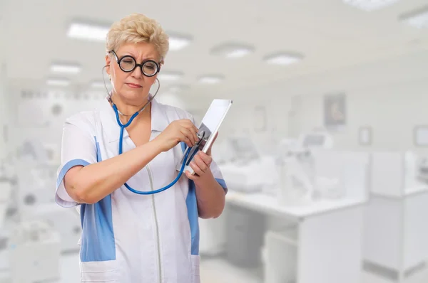 Śmieszne starsze lekarz słuchać tabliczka pc przez stetoskop — Zdjęcie stockowe