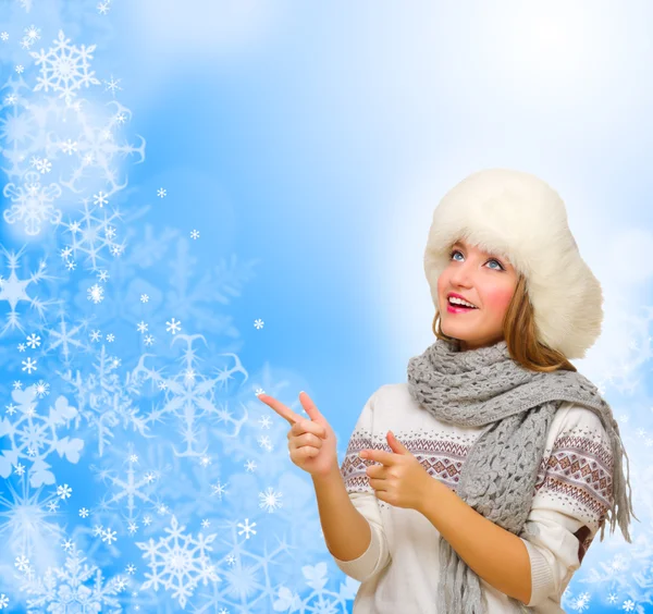 Girl shows pointing gesture on winter background — Stock Photo, Image