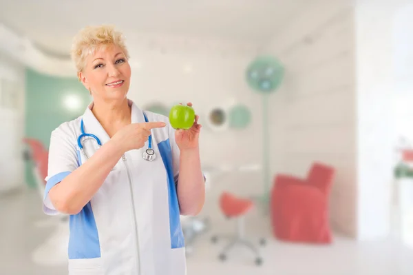 Reife Ärztin mit Apfel in Arztpraxis — Stockfoto