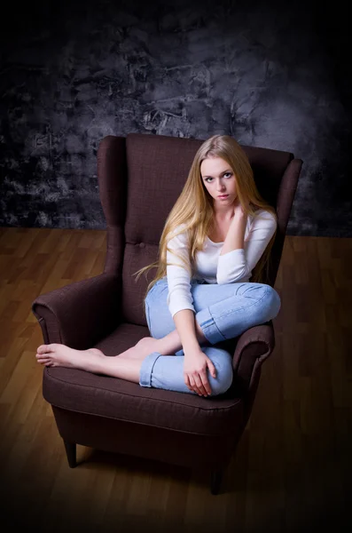 Κορίτσι να καθίσει στην καρέκλα σε φόντο γκρι τοίχων — Φωτογραφία Αρχείου