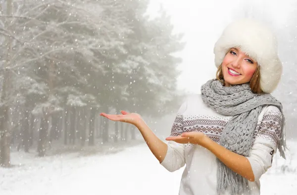 Young woman in fur hat shows welcome gesture at forest — Stock Photo, Image
