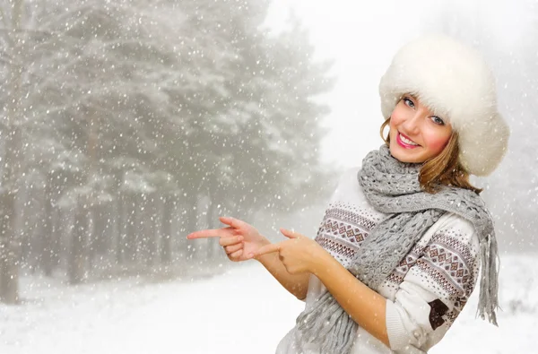 Young girl shows pointing gesture at snowy forest — Stock Photo, Image