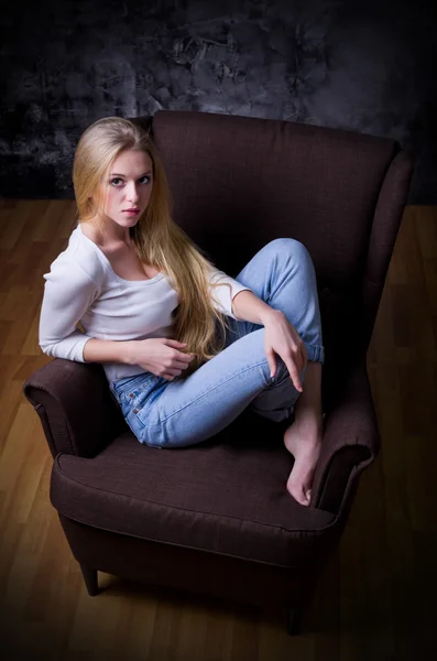 Young girl sit in chair on grey wall background — Stock Photo, Image