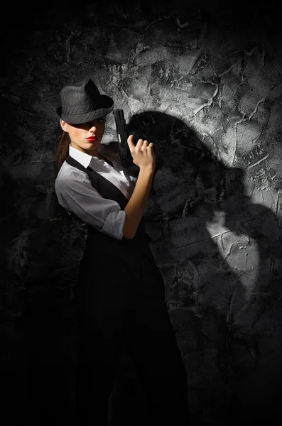 Retrato de mujer joven en estilo varonil con pistola en la pared gris —  Fotos de Stock