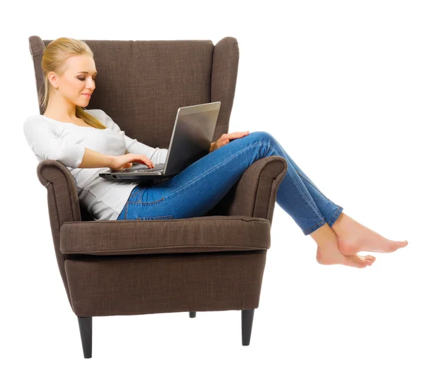 Молодая девушка в джинсах на стуле с ноутбуком — стоковое фото