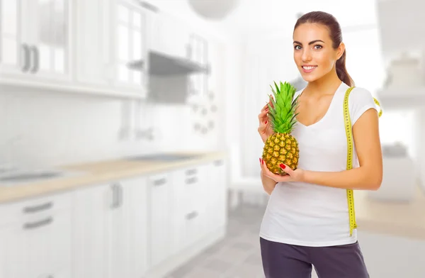 Chica joven con piña en la cocina —  Fotos de Stock