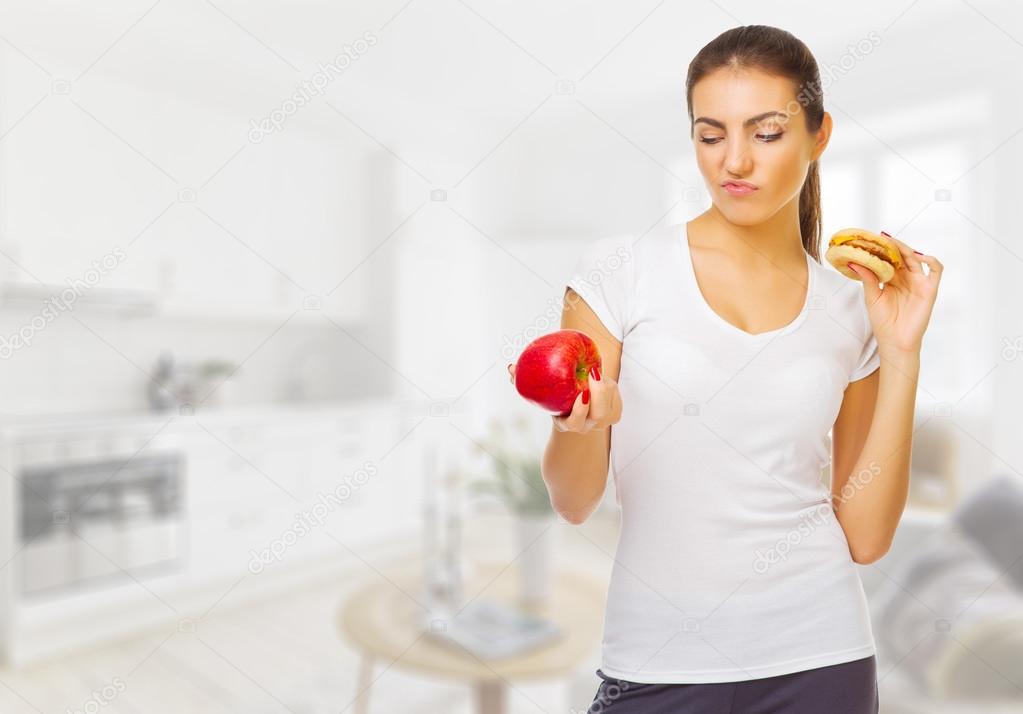Young healthy woman with apple and hamburger