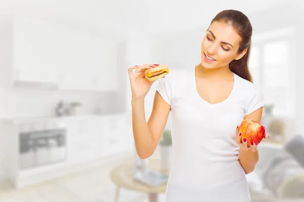 Chica joven con manzana y hamburguesa en la sala de luz — Foto de Stock